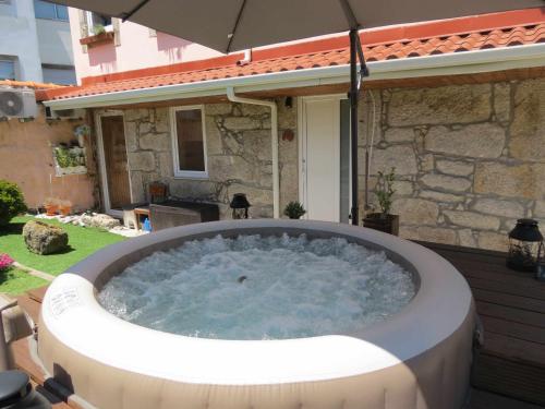 a hot tub in a backyard with an umbrella at Ruby Charm Houses 2 AL in Porto