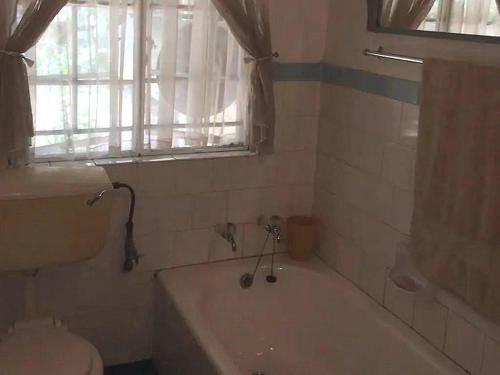 a bathroom with a tub and a sink and a window at Goederus Guest Farm in Sterkspruit