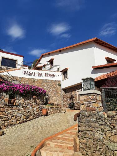 a white building with a stone wall and stairs at Casal da Serra in Penha Garcia