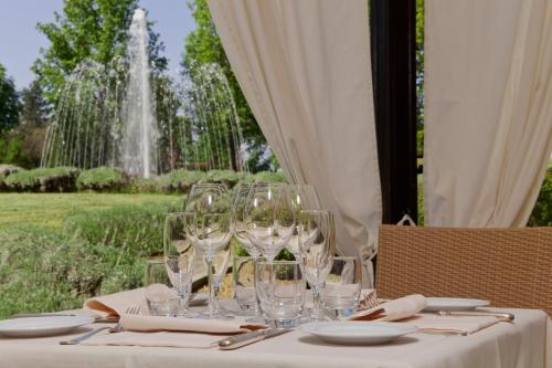 a table with wine glasses and a fountain in the background at Relais Villa Pomela in Novi Ligure