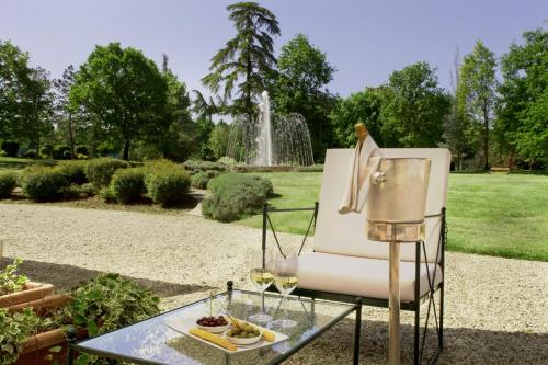 a chair with a glass table and a fountain at Relais Villa Pomela in Novi Ligure