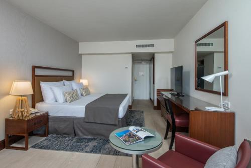 a hotel room with a bed and a desk with a mirror at King Solomon by Isrotel Collection in Eilat