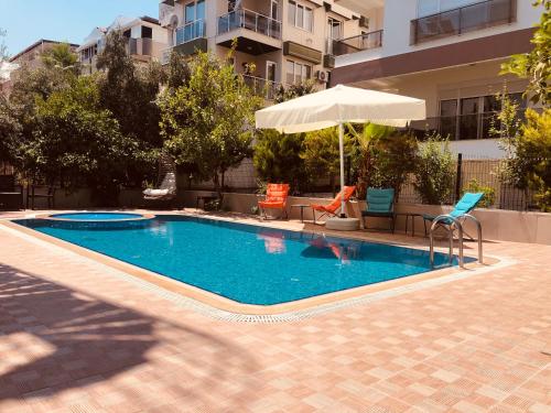 a swimming pool with two chairs and an umbrella at Ale Park Hotel Apartments in Antalya