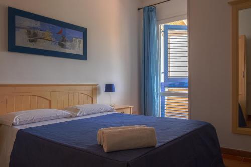 um quarto com uma cama com um cobertor azul e uma janela em Orsola Apartments em Favignana