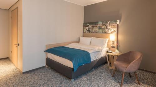 a hotel room with a bed and a chair at Holiday Inn Düsseldorf City – Toulouser Allee by IHG in Düsseldorf