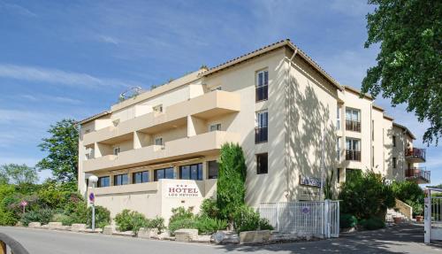 a large building on the side of a street at Hotel Les Nevons in LʼIsle-sur-la-Sorgue