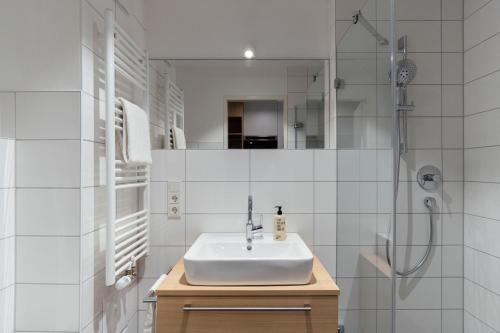 uma casa de banho branca com um lavatório e um chuveiro em KONCEPT HOTEL Neue Horizonte em Tübingen