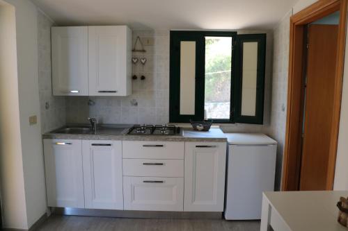 uma cozinha com armários brancos, um lavatório e uma janela em Albergo"Villa Biscotti" em Peschici