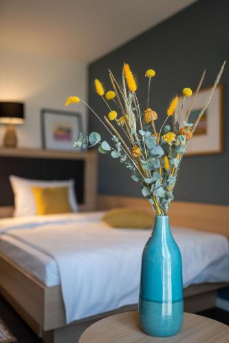 a blue vase with flowers on a table in a bedroom at KONCEPT HOTEL Neue Horizonte in Tübingen
