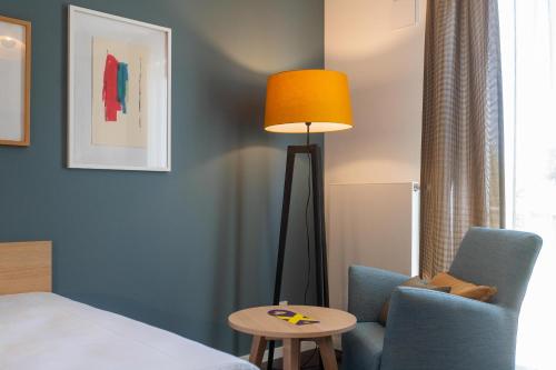 a room with a bed and a table and a lamp at KONCEPT HOTEL Neue Horizonte in Tübingen
