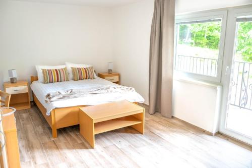 a white bedroom with a bed and a balcony at Zelena Oaza in Zgornja Kungota