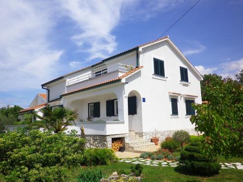 a white house with black shuttered windows on it at Apartments Marinovic in Brzac
