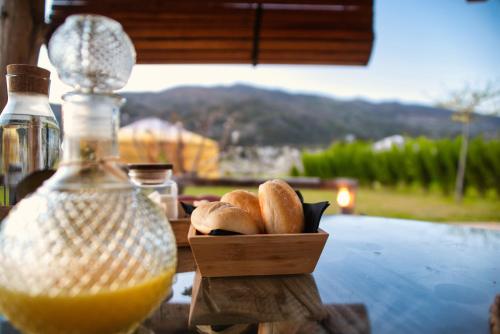 Un tazón de madera con bagels junto a una botella de jugo de naranja en Glamping El Jardín De Las Delizias Valle Del Jerte, en Casas del Castañar
