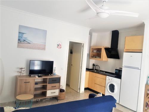 a living room with a blue couch and a kitchen at Conil Centro & Playa, descanso perfecto, Aire Ac y WIFI -SOLO FAMILIAS Y PAREJAS- in Conil de la Frontera