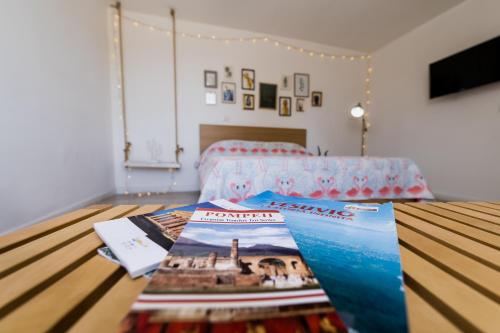 Cette chambre comprend un lit et une table avec des magazines. dans l'établissement Flamingo B&B, à Pompéi