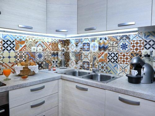 a kitchen with a sink and tiles on the wall at Achi's House in Lefkada