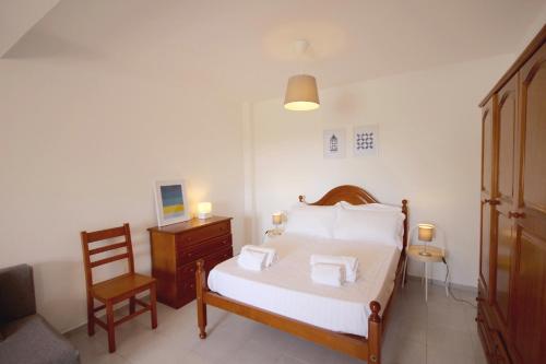 - une chambre avec un lit doté de draps blancs et d'une chaise dans l'établissement Villa Alvor 6 by amcf, à Alvor