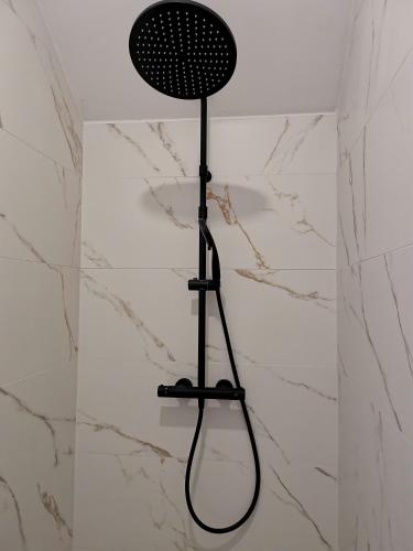 une douche avec un pommeau de douche noir sur un mur dans l'établissement Studio cocooning, à Banyuls-dels-Aspres