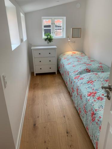 a small bedroom with a bed and a dresser and window at Præstegade 11 in Ribe