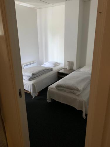 two beds in a hotel room with white sheets at Skuldelev kro in Skibby