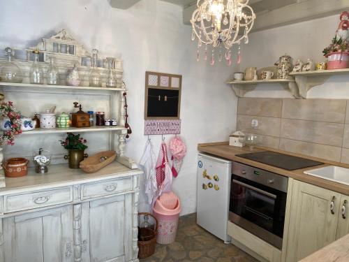 a kitchen with white cabinets and a chandelier at Rosa Villa in Szigliget