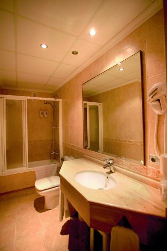 a bathroom with a sink and a toilet and a mirror at Hotel Vent de Mar in Puerto de Sagunto
