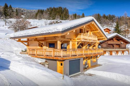 a log cabin with snow on the roof at Chalet Marinaka - OVO Network in Manigod