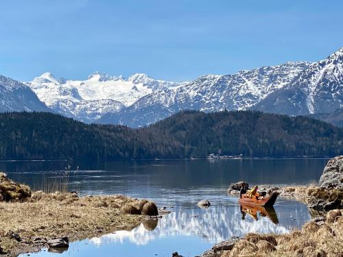 a boat on a lake with snow covered mountains at Bergvilla Oberon - Your Austrian Home in Bad Aussee