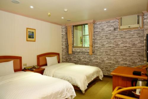 Zimmer mit 2 Betten und Ziegelwand in der Unterkunft Lidu Hotel in Suao
