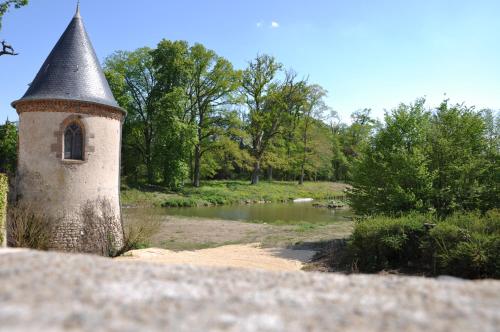 a building with a tower next to a river at Château Origny - Moulins in Neuvy