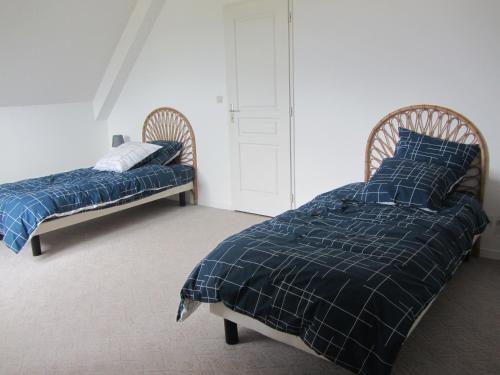 - 2 lits avec couette et oreillers bleus dans une chambre dans l'établissement La Villa Marina, à Donville-les-Bains