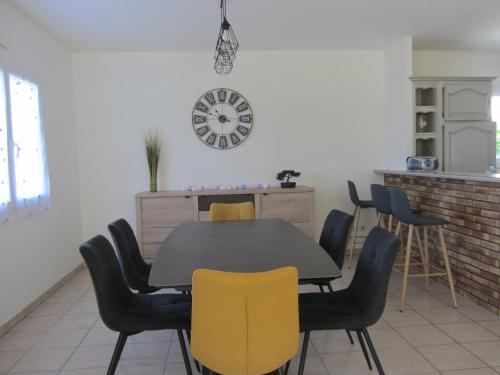 une table à manger avec des chaises et une horloge murale dans l'établissement La Villa Marina, à Donville-les-Bains