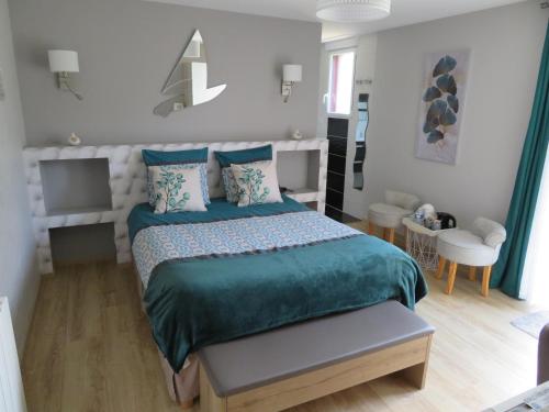 a bedroom with a large bed with a green comforter at Chambres d'Hotes La Maison Neuve in Saint-Loup