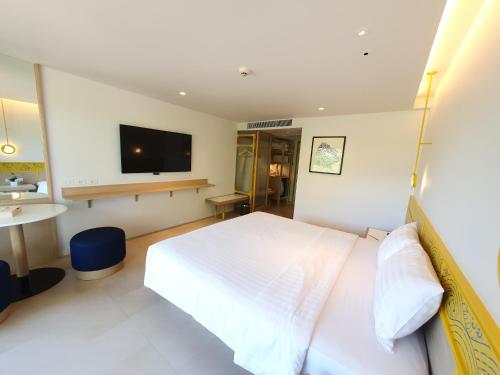 a bedroom with a white bed and a flat screen tv at Novotel Rayong Rim Pae Resort in Klaeng