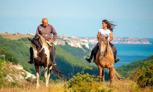 a man and a woman riding horses in a field at Happy Studio Sea View in Topola