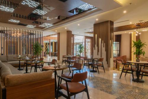ジッダにあるEmerald Hotelのテーブルと椅子、ソファ付きのレストラン
