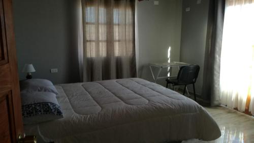 1 dormitorio con cama, escritorio y ventana en TIK'A WASI SUP, en San Pedro de Atacama