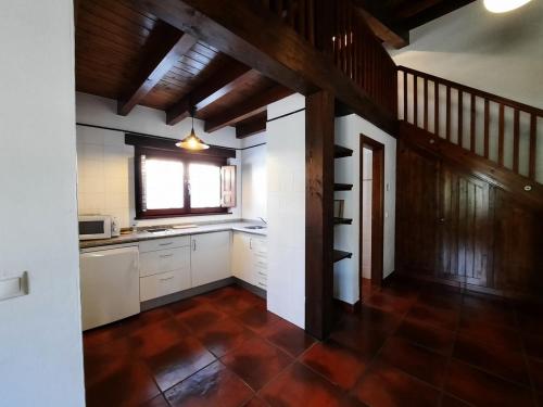 a kitchen with white cabinets and a brown tile floor at LOFT ROBLE - Chousa Verde in Vegacervera