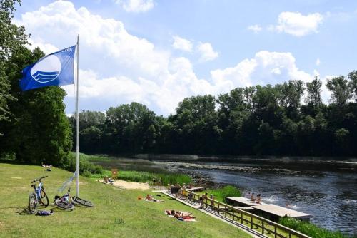 una bandiera blu sull'erba vicino a un fiume di Vintage Rooms a Kuldīga