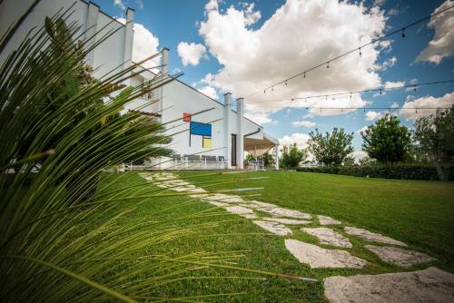 a building with a grassy yard with a stone pathway at Locanda del Pino in Ginosa Marina