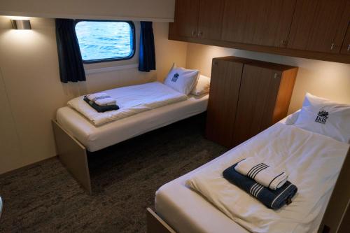 a small room with two beds and a window at Hotelboat Iris in Amsterdam