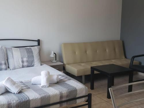 a bedroom with a bed and a couch and a table at Lavrio port-centre 1bdr Apt with balcony wash machine in Lavrio