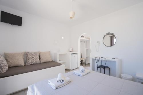 a white living room with a couch and a table at Zisis Pension in Agios Stefanos