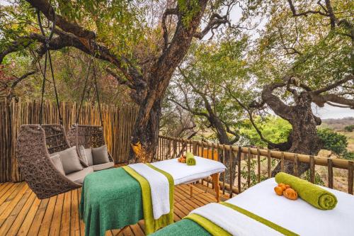two beds on a deck with a tree at Kruger Gate Hotel in Skukuza