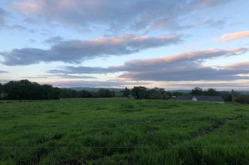 a field of green grass with a fence in the foreground at The Paddocks Cabin - Stylish, Cozy & Private in Killarney