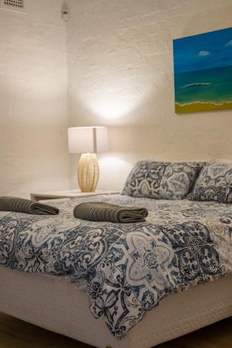 a bedroom with a bed with a blue and white comforter at 16 st Johns - Apartment in Port Shepstone