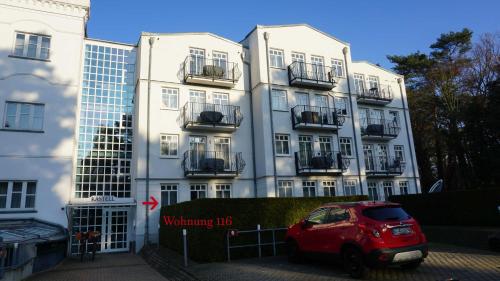 a red car parked in front of a building at Appartements Haus Tannenburg in Ahlbeck