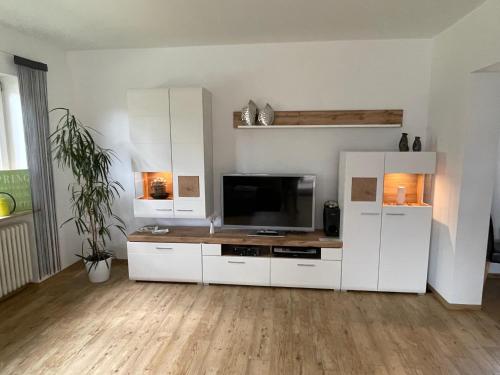 ein Wohnzimmer mit weißen Schränken und einem Flachbild-TV in der Unterkunft Ferienwohnung Föhrenweg in Neumarkt in der Oberpfalz