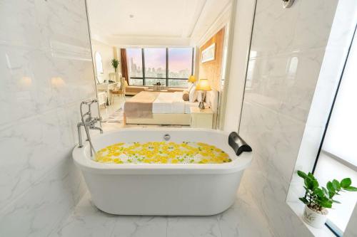 a bath tub in a bathroom with a bedroom at Brilliant Hotel - Afternoon Tea Inclusive in Da Nang