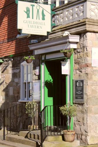 a green front door of a building with potted plants at Guildhall Tavern Hotel & Restaurant in Denbigh